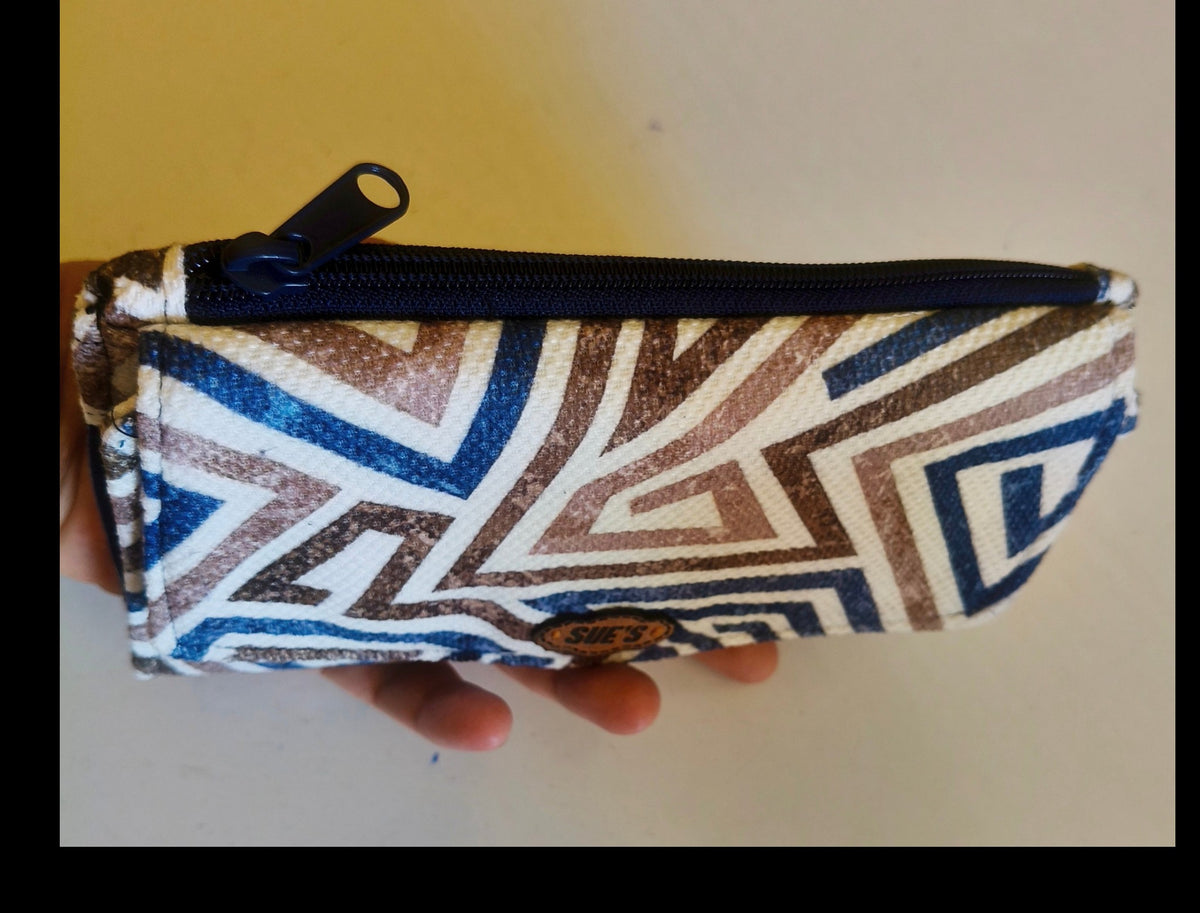 Suepatchwork blue and brown geometric print fabric trifold wallet with a secure zip closure held in a hand