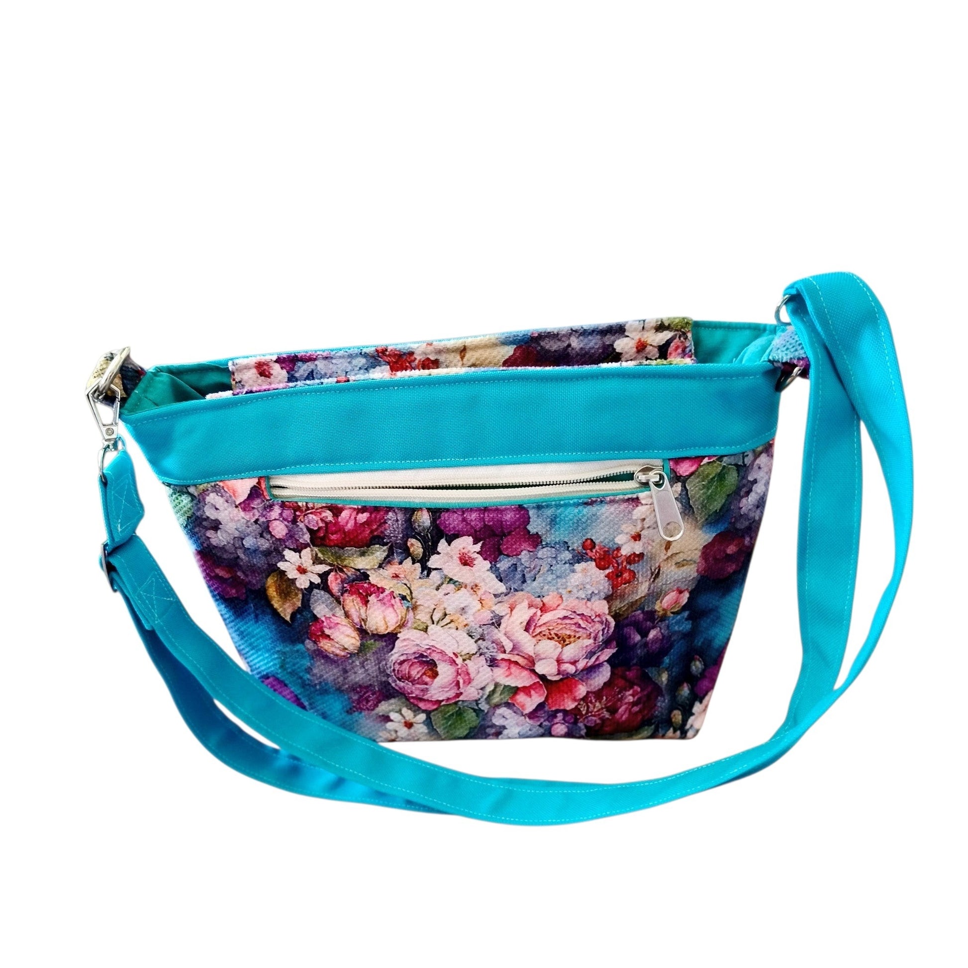 Suepatchwork floral crossbody bag with vibrant rose print, teal trim, adjustable strap, and exterior zip pocket.