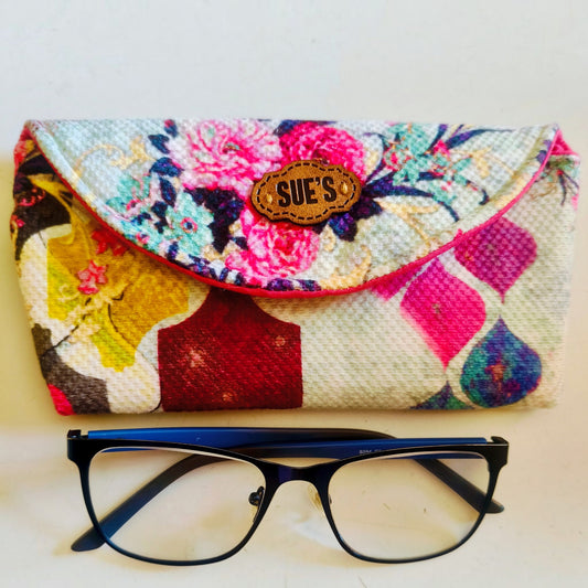 Suepatchwork floral fabric glasses case with magnetic closure and Sue's leather label, shown with black eyeglasses.