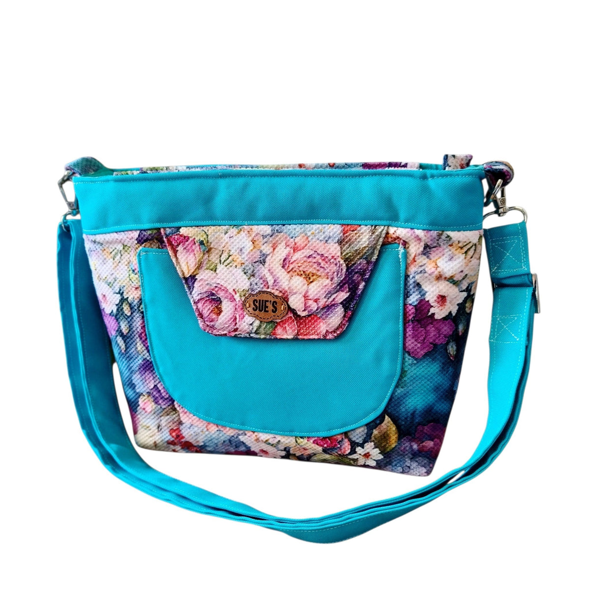 Suepatchwork floral crossbody bag in turquoise with a front pocket and adjustable strap, handmade fabric design.
