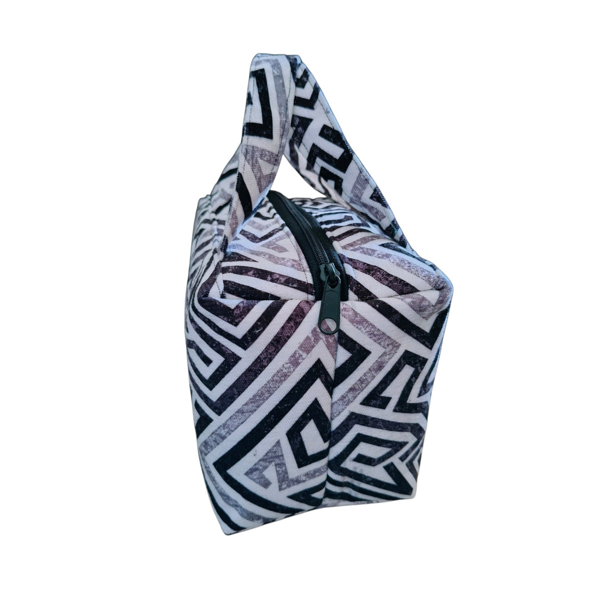 Suepatchwork handcrafted fabric makeup bag with a black and white geometric pattern and a convenient top handle.