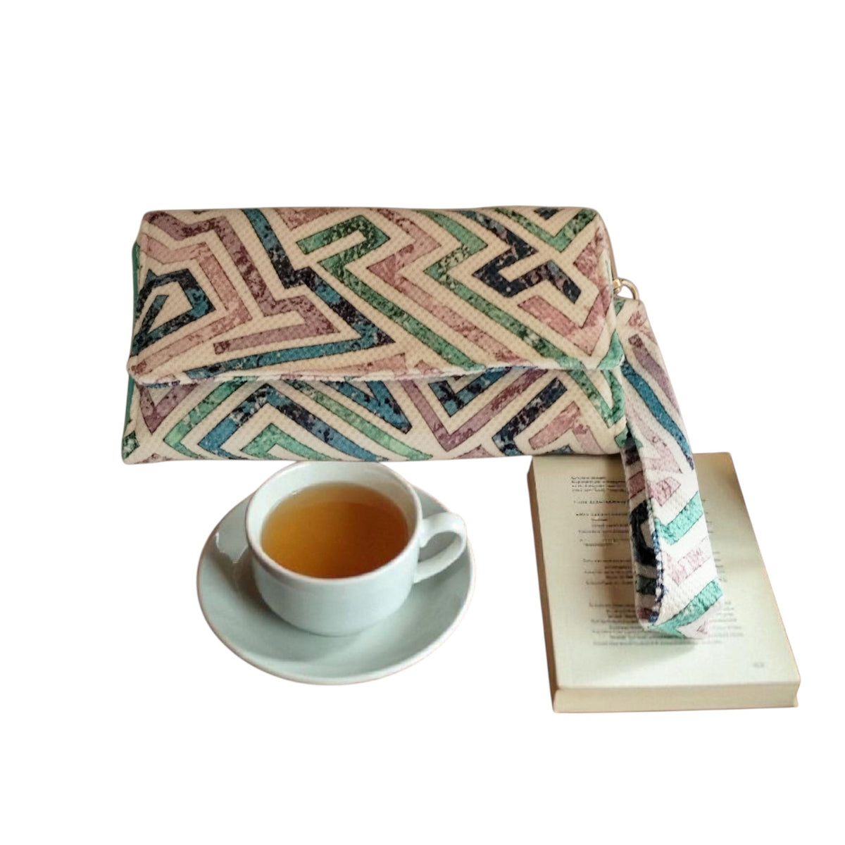 Suepatchwork handcrafted fabric wallet with geometric print, detachable strap, and cotton lining next to a tea cup.