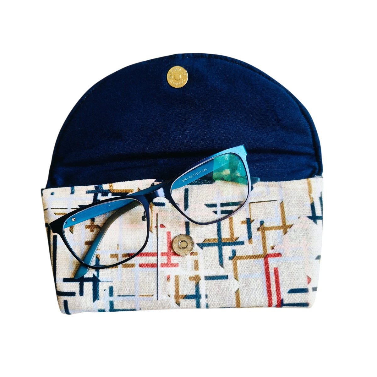 Suepatchwork handmade fabric glasses case with a geometric pattern and navy blue flap featuring a magnetic closure