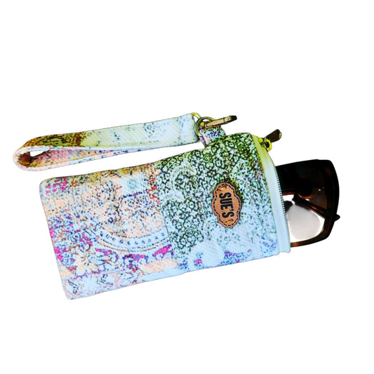 Suepatchwork handmade patchwork quilted long glasses case with a wrist strap and leather logo tag on a wooden table.