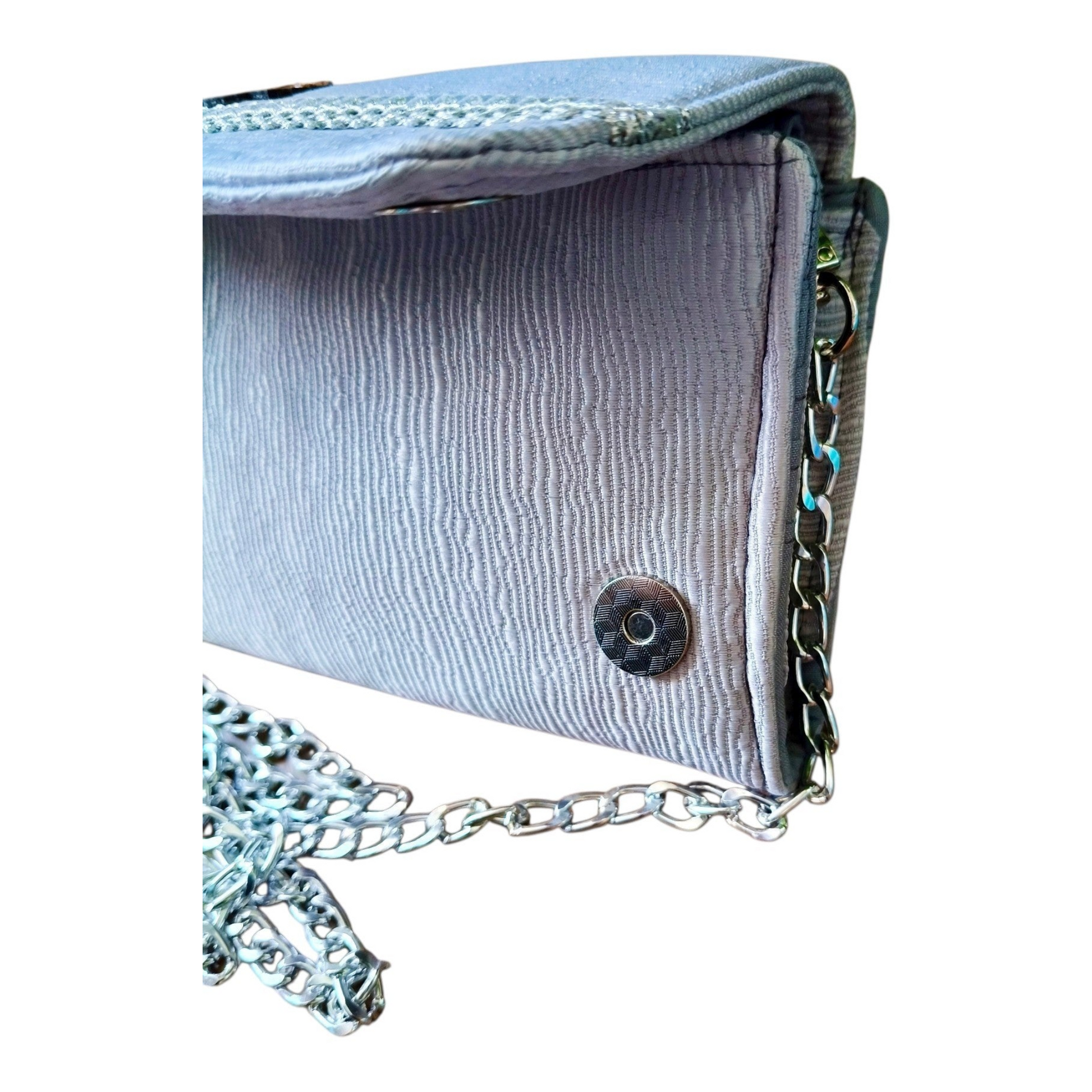 Suepatchwork silver evening wallet with detachable metal chain strap, featuring textured fabric and side snap detail.